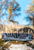 Metal Man Cave novelty sign with spanner ends resting on a mossy rock outdoors
