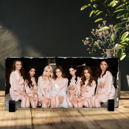 Freestanding rectangular photo slate displaying a wedding party photograph on a wooden shelf